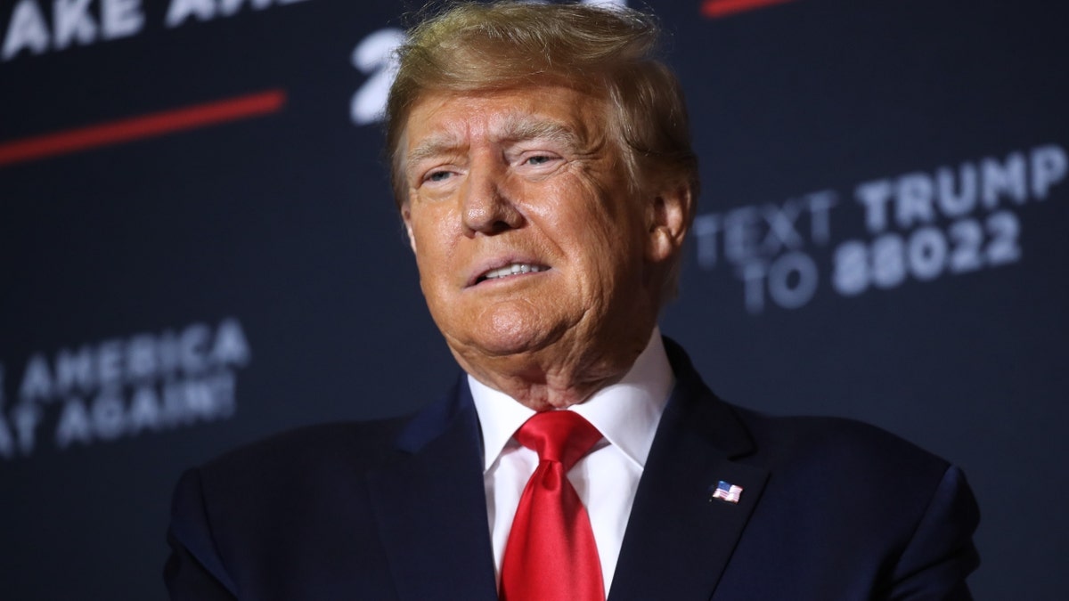 Donald Trump in red tie, dark coat at campaign event