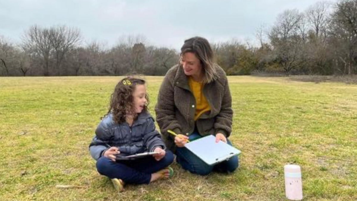 Homeschool parent teaches her kid outdoors