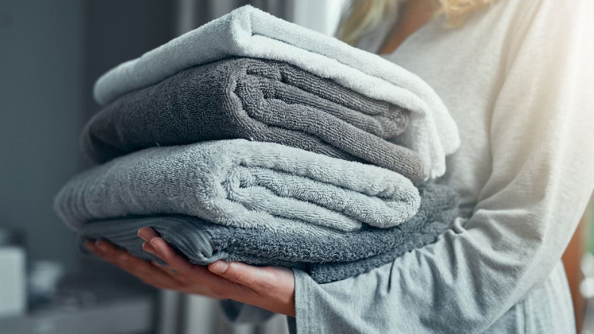 Woman carries stack of bath towels