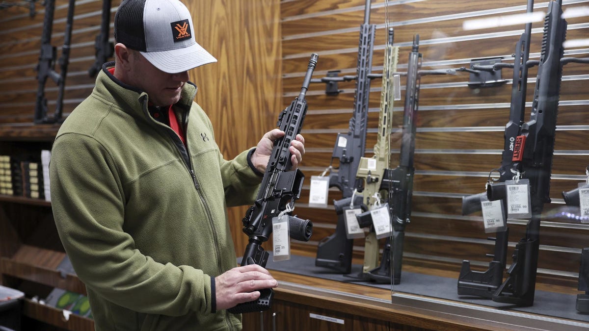 A firearm store owner shows off a Heckler & Koch brand rifle