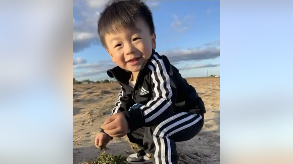 Jasper Wu squats and smiles on the beach