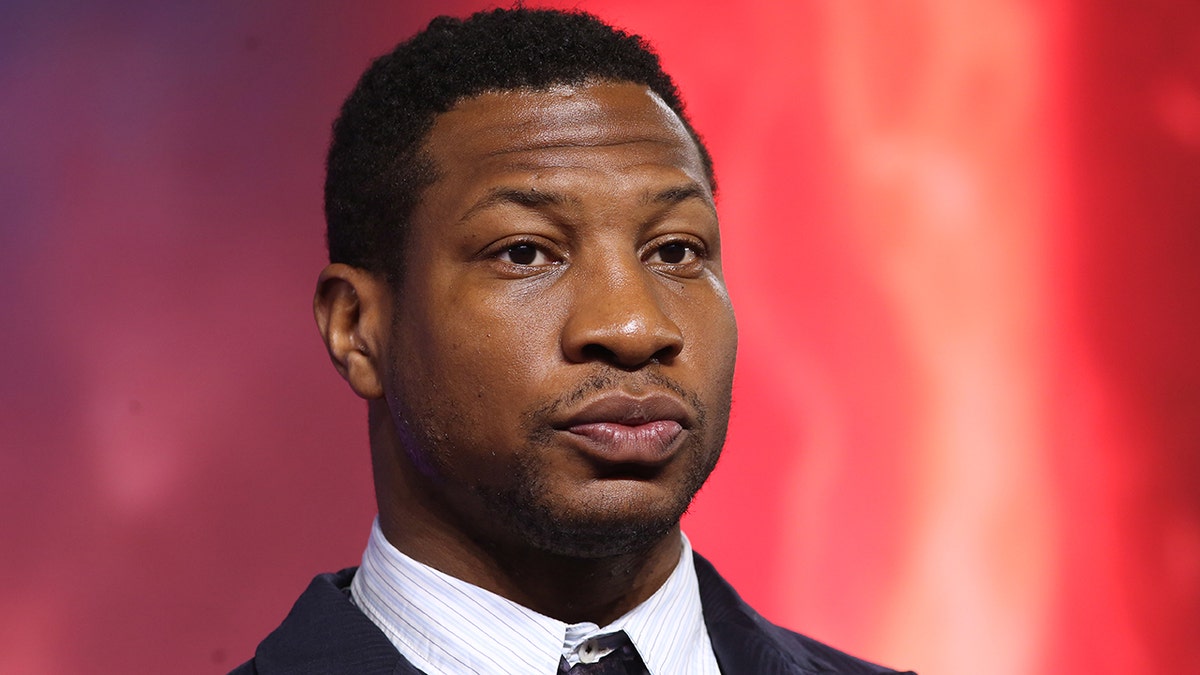 Jonathan Majors wears black suit.