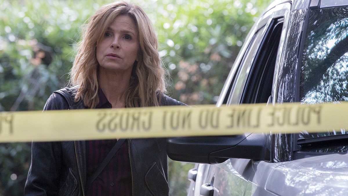 Kyra Sedgwick stands behind yellow police tape on episode of The Closer