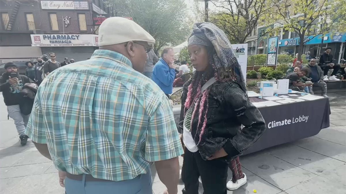 Woman looks at man as he yells at her during Earth Day Event