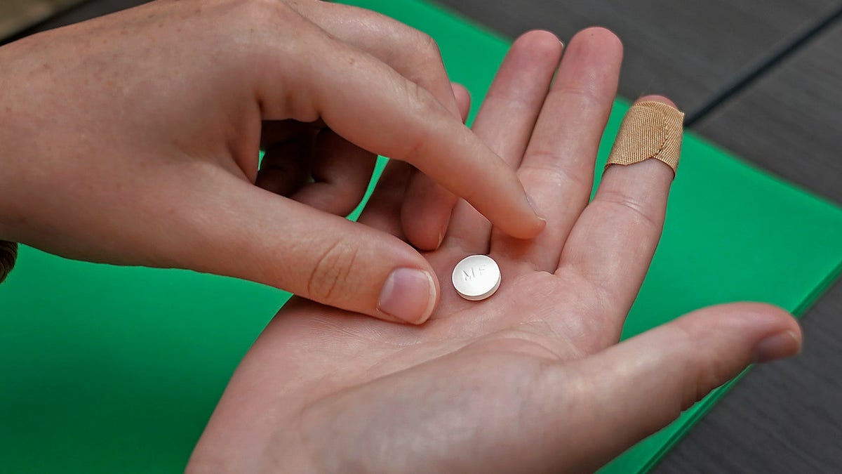 A woman holds the first of two combination pills, mifepristone, which will induce an abortion
