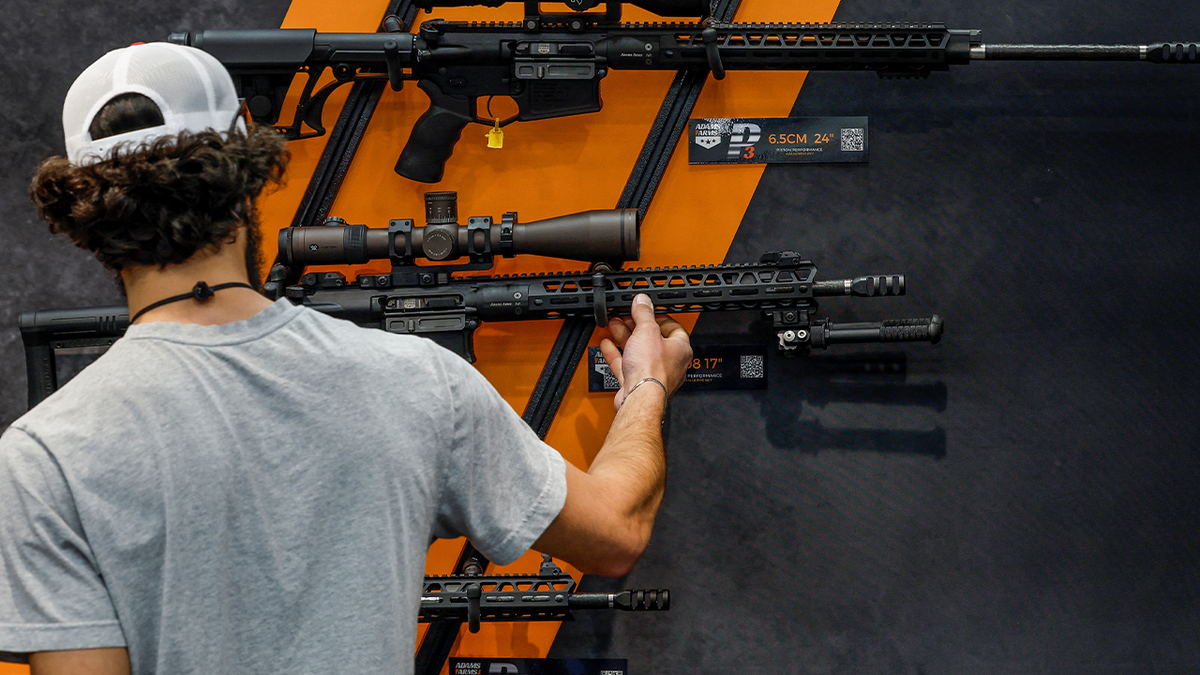 man looking at rifle on wall at NRA convention