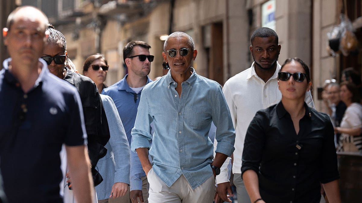 Barack and Michelle Obama walk through Barcelona streets with security