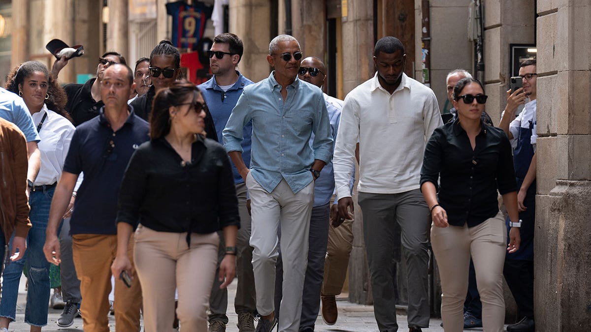 Barack and Michelle Obama walk through Barcelona streets with security