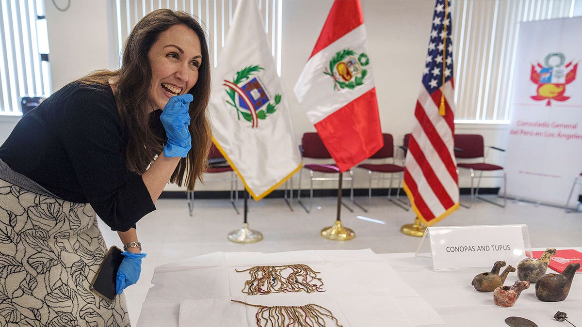 Claudia Bastante, Peruvian Deputy-Counsel in Los Angeles and professional archaeologist, smiles as she looks at an artifact in Los Angeles on April 21, 2023. Several Peruvian antiquities were returned to its home country during a ceremony at the Los Angeles, California, consulate.