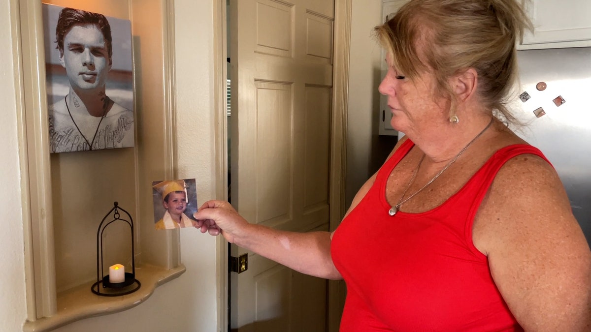 A woman looks at an old photo of her son