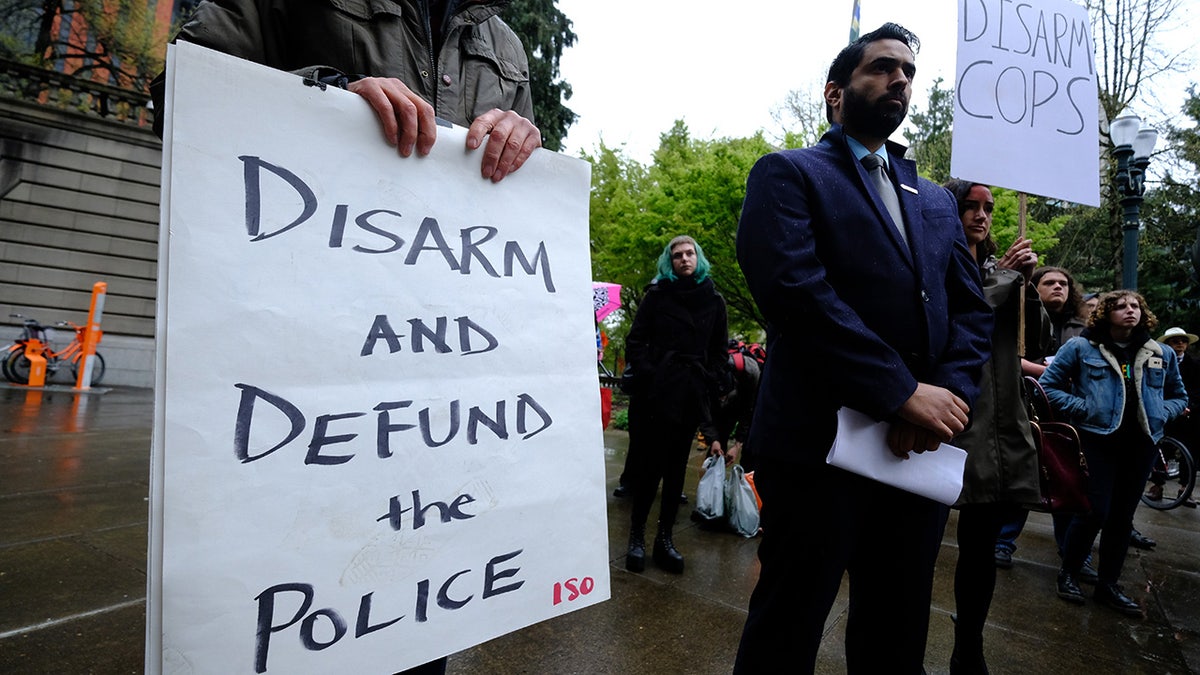 Protesters hold signs reading "disarm cops" and "defund the police" in Portland, Oregon