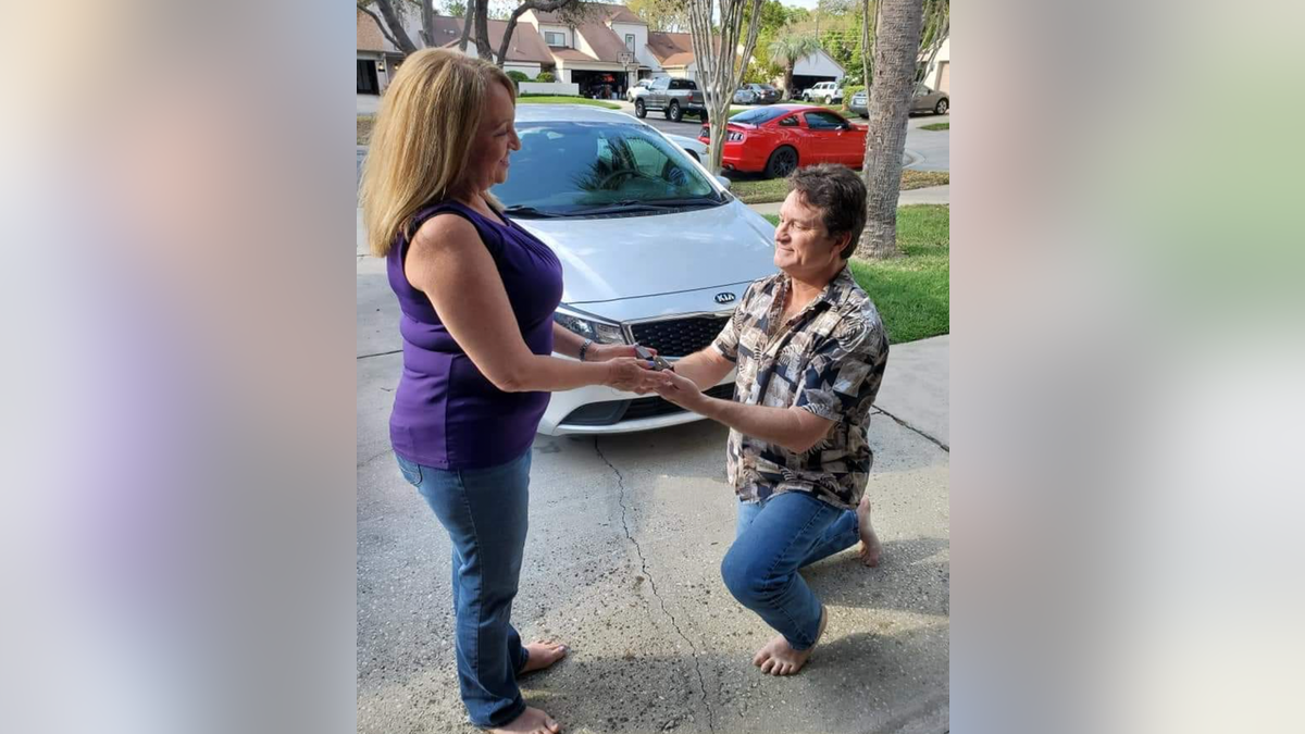 Randall Cooke shown on one knee proposing to his wife, Kathy.