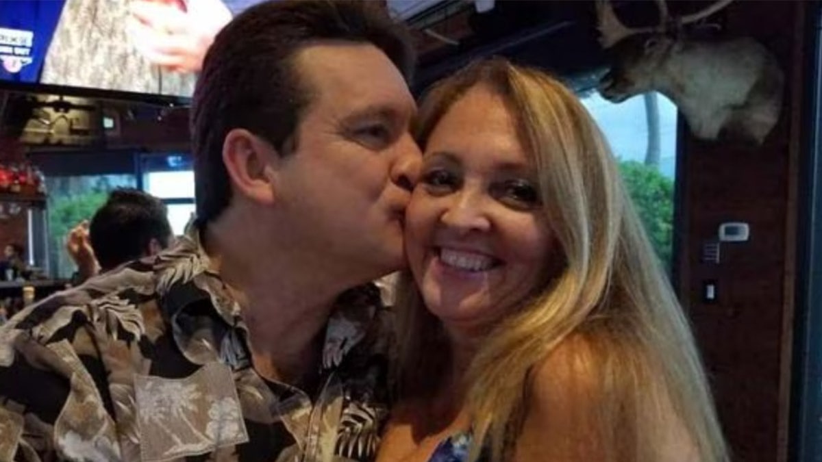 Randall Cooke kisses his wife, Kathy on the cheek in a restaurant.