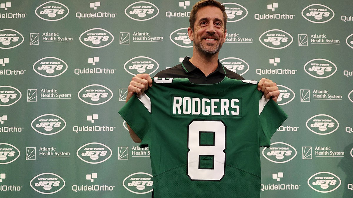 Aaron Rodgers holds jets jersey at conference