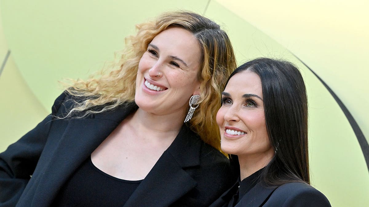Rumer Willis and Demi Moore pose in front of green background 