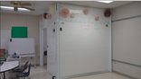 An 8-by-8 foot room stands in the corner of a classroom. On the outside is dry erase material with classroom decorations on it