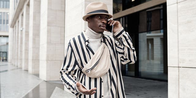 Man dressed in a white-and-black striped suit putting his phone to his ear