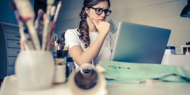Woman wears glasses and looks stressed while at her computer