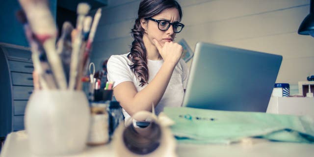 Woman wears glasses and looks stressed while at her computer