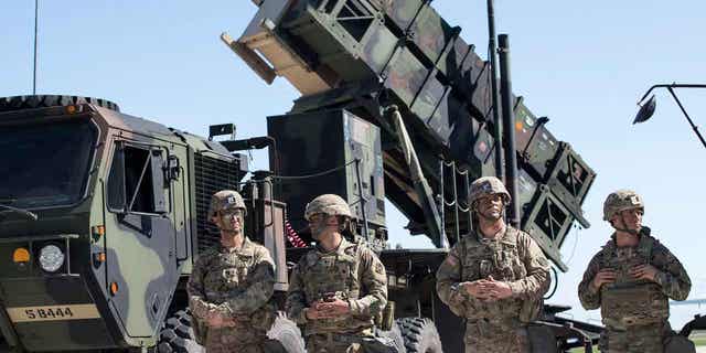 Members of US 10th Army Air and Missile Defense Command stands next to a Patriot