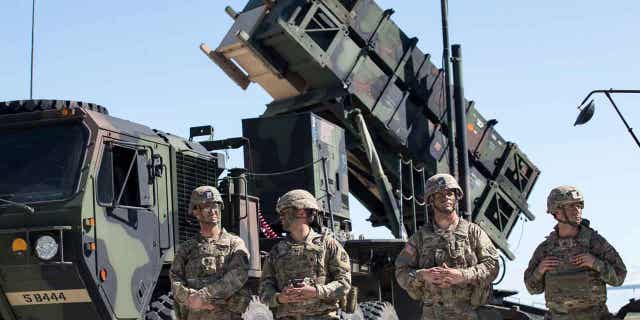 Members of US 10th Army Air and Missile Defense Command stands next to a Patriot