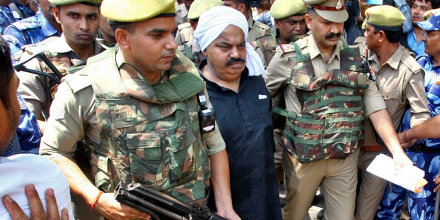 Police officers escort Atiq Ahmed, a former lawmaker accused in several criminal cases, outside a court in Prayagraj, India, April 13, 2023. (Reuters/Ritesh Shukla)