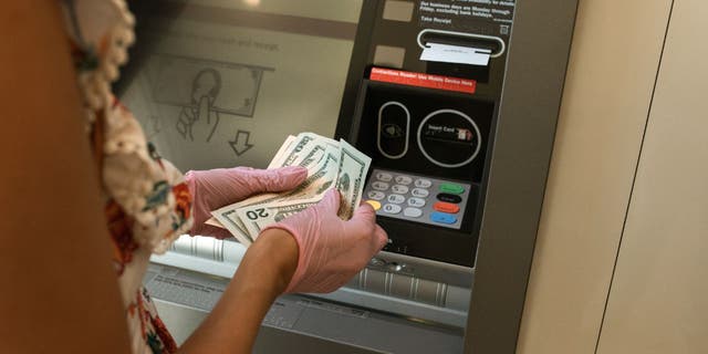 Woman holding cash in front of an ATM