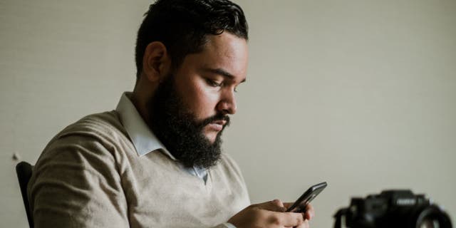 No se deje engañar por estos engañosos mensajes de texto falsos 6 Un hombre mirando su teléfono