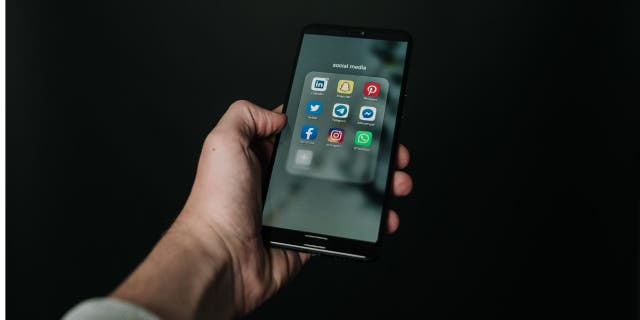 Someone holding up their phone with all of the social media app icons.