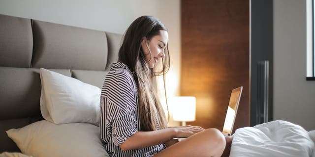 Woman on laptop sitting on the bed