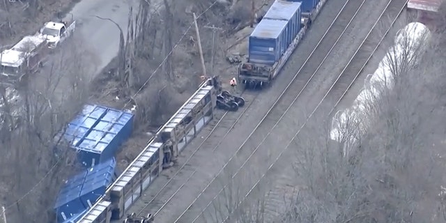 Los funcionarios caminan cerca de la escena del descarrilamiento de un tren de carga, el jueves 23 de marzo de 2023, en Ayer, Massachusetts. 