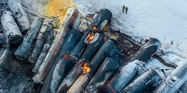 Los bomberos se paran cerca de los vagones de tren apilados, cerca de Raymond, Minnesota, el jueves 30 de marzo de 2023, la mañana después del descarrilamiento de un tren de carga BNSF. 