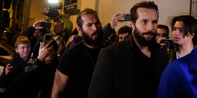 Young fans and media surround Andrew Tate, left, and his brother Tristan as they leave a police detention facility in Bucharest, Romania, after his release from prison on Friday March 31, 2023. An official on Friday said Tate, the divisive internet personality who has spent months in a Romanian jail on suspicion of organized crime and human trafficking, has won an appeal to replace his detention with house arrest. (AP Photo/Alexandru Dobre)