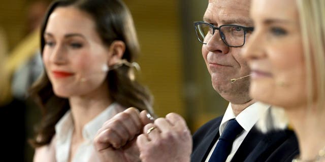 Chair of SDP Sanna Marin, left, and chair of The Finns party Riikka Purra, right, look on as National Coalition Party chair Petteri Orpo cheers at the Finnish parliamentary elections media reception at the Finnish Parliament in Helsinki, Finland on Sunday, April 2, 2023. 