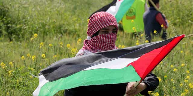Los palestinos ondean banderas durante una marcha a lo largo de la valla fronteriza con Israel, al este de la ciudad de Gaza, el 30 de marzo de 2023. Un grupo israelí de derechos humanos dijo que Israel tiene detenidos a más de 1.000 palestinos sin cargos.  Este es el mayor número de detenidos en Israel desde 2003. 