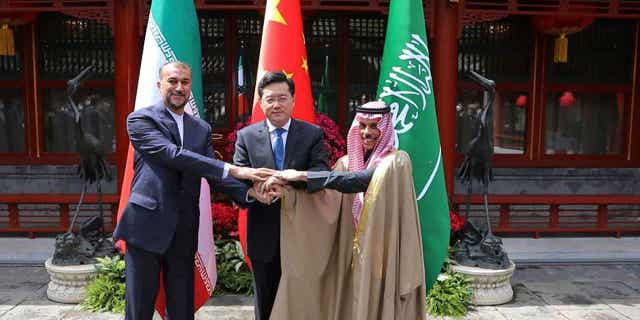 Iran's Foreign Minister Hossein Amirabdollahian, left, shakes hands with his Saudi Arabian counterpart Prince Faisal bin Farhan Al Saud, right, and Chinese counterpart Qin Gang in Beijing on April 6, 2023. 