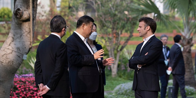 Chinese President Xi Jinping, second left, and French President Emmanuel Macron speak at the Guangdong Provincial Governor's Residence Garden in Guangzhou, China, Friday, April 7, 2023. 