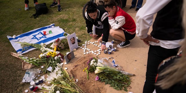 People gather and lay flowers at the site where Alessandro Parini, an Italian tourist, was killed in a Palestinian attack, in Tel Aviv, Israel, Saturday, April 8, 2023. Israeli authorities said an Italian tourist was killed and five other Italian and British citizens were wounded Friday when a car rammed into a group of tourists in Tel Aviv.