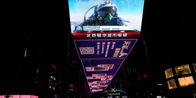 An outdoor screen depicts a Chinese fighter jet pilot giving a thumbs up in the recently concluded Joint Sword exercise around Taiwan during the evening news broadcast in Beijing, April 10, 2023.