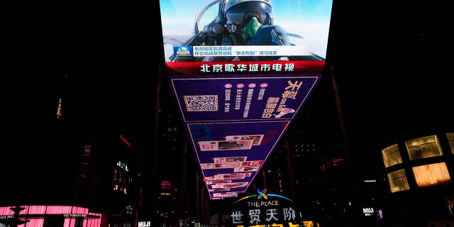 An outdoor screen depicts a Chinese fighter jet pilot giving a thumbs up in the recently concluded Joint Sword exercise around Taiwan during the evening news broadcast in Beijing, April 10, 2023.