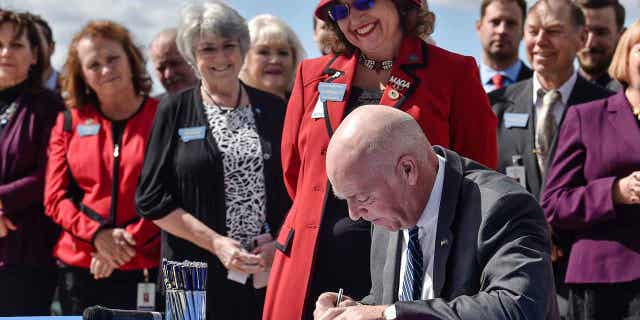 Republican Gov. Greg Gianforte signs a bill restricting access to abortion in Montana as state Rep. Lola Sheldon-Galloway watches in Helena, Montana, on April 26, 2021. Montana's Planned Parenthood filed a preemptive lawsuit on April 10, 2023, seeking to stop legislation that would ban a common abortion method.