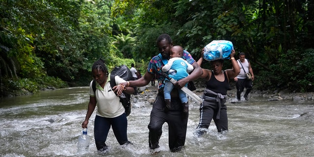 FILE - Haitian migrants wade through a river as they cross the Darien Gap, from Colombia into Panama, hoping to reach the U.S., Oct. 15, 2022. 