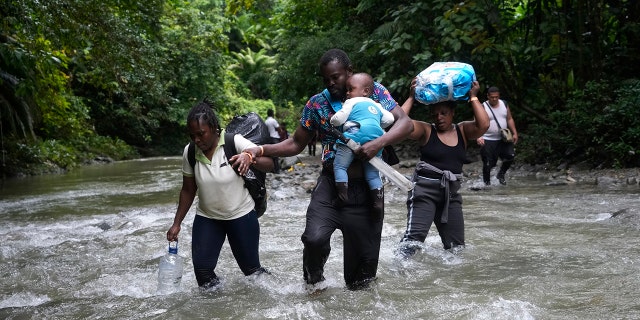 FILE - Haitian migrants wade through a river as they cross the Darien Gap, from Colombia into Panama, hoping to reach the U.S., Oct. 15, 2022. 