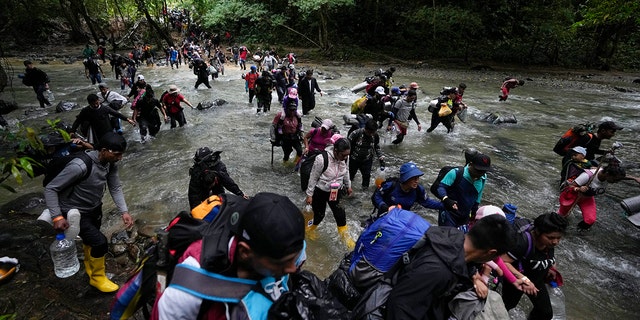 Migrantes, en su mayoría venezolanos, cruzan un río durante su viaje a través del Tapón del Darién desde Colombia hacia Panamá, con la esperanza de llegar a EE. UU., el 15 de octubre de 2022. 