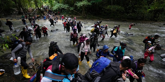 Migrants, mostly Venezuelans, cross a river during their journey through the Darien Gap from Colombia into Panama, hoping to reach the U.S., Oct. 15, 2022. 