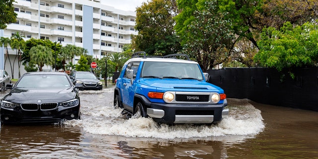 Cars go through the flooded road cause by heavy rains at North Bay Rd and 179th Dr. in Sunny Isles Beach, Fla., Wednesday, April 12, 2023. 