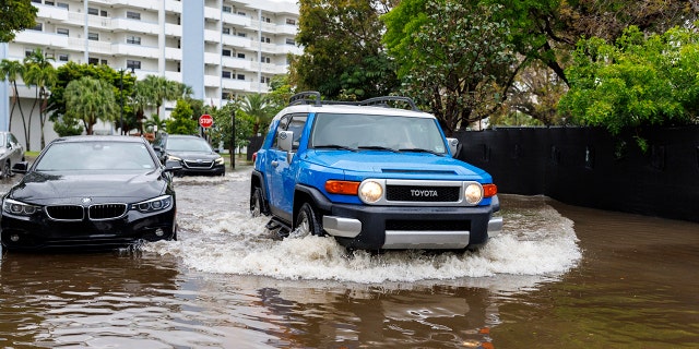 Cars go through the flooded road cause by heavy rains at North Bay Rd and 179th Dr. in Sunny Isles Beach, Fla., Wednesday, April 12, 2023.