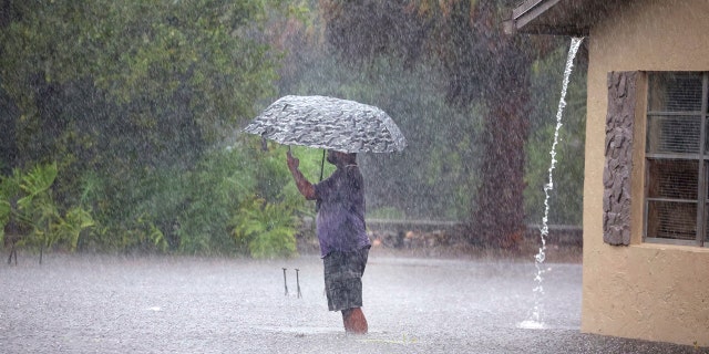 A man stops to take a photo of a flooded neighborhood at SW 3rd Street and SW 4th Ave in Dania Beach, Fla., Wednesday, April 12, 2023.