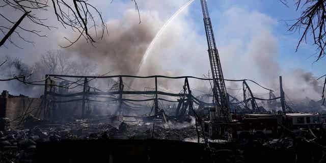 Firefighters pour water on an industrial fire in Richmond, Indiana, on April 13, 2023. The major flames from the fire have been extinguished, but crews are still working to extinguish hot spots.