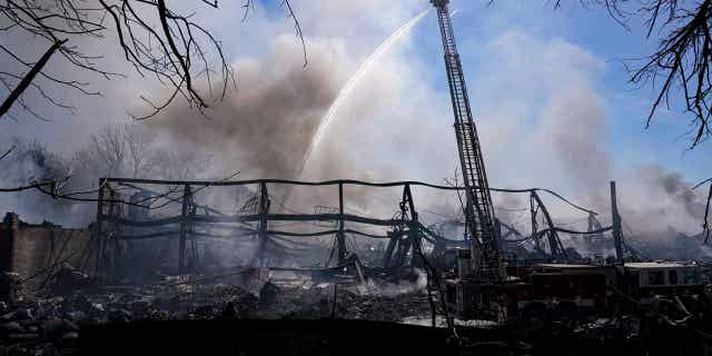 Firefighters pour water on an industrial fire in Richmond, Indiana, on April 13, 2023. The major flames from the fire have been extinguished, but crews are still working to extinguish hot spots.